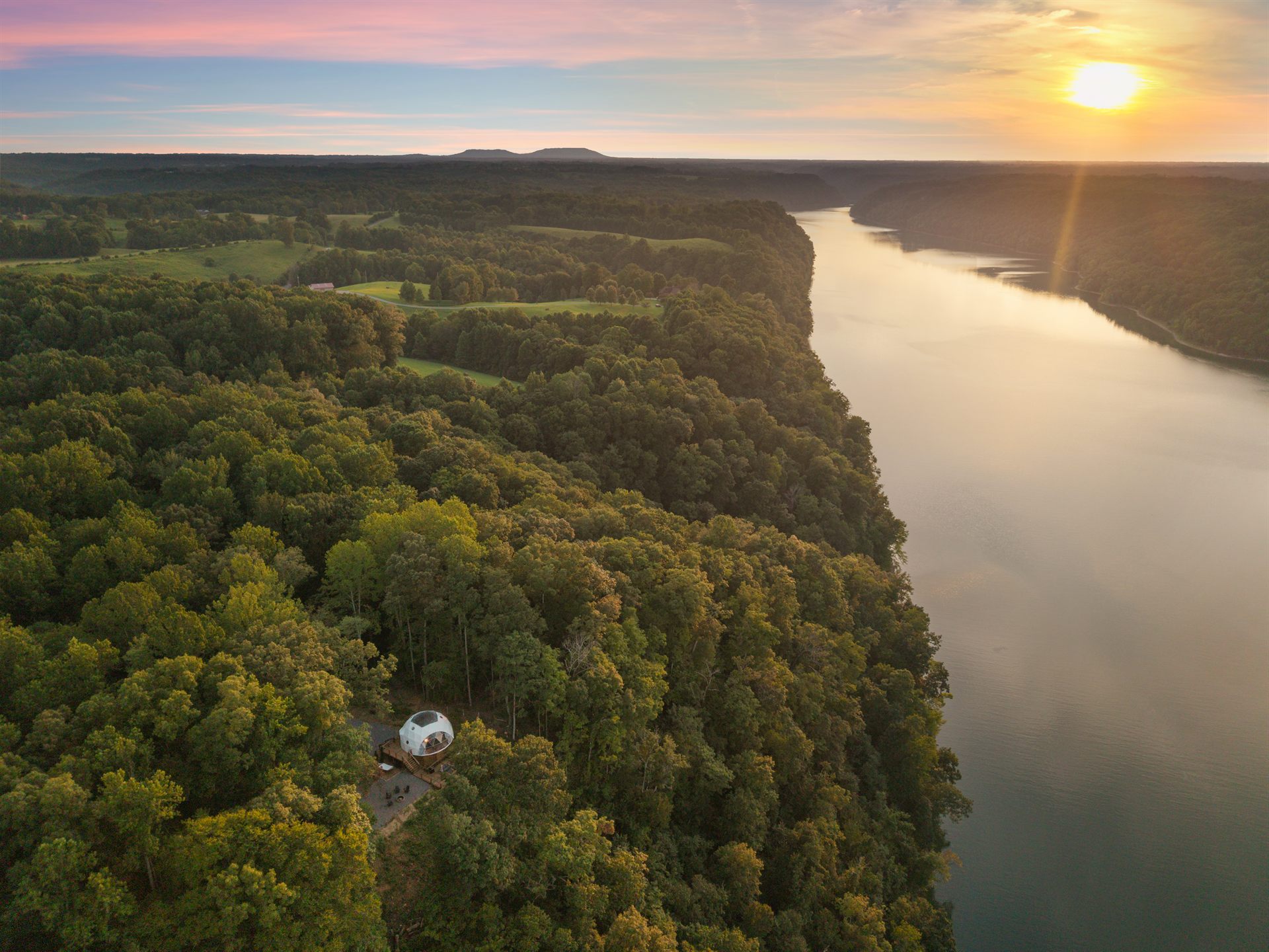 Sunset aerial view of the lake and wooded peninsula surrounding Nestled Inn